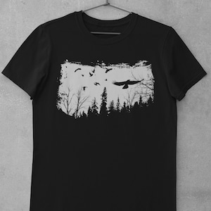 May include: Black t-shirt with a white graphic print of a forest silhouette with birds flying over it.