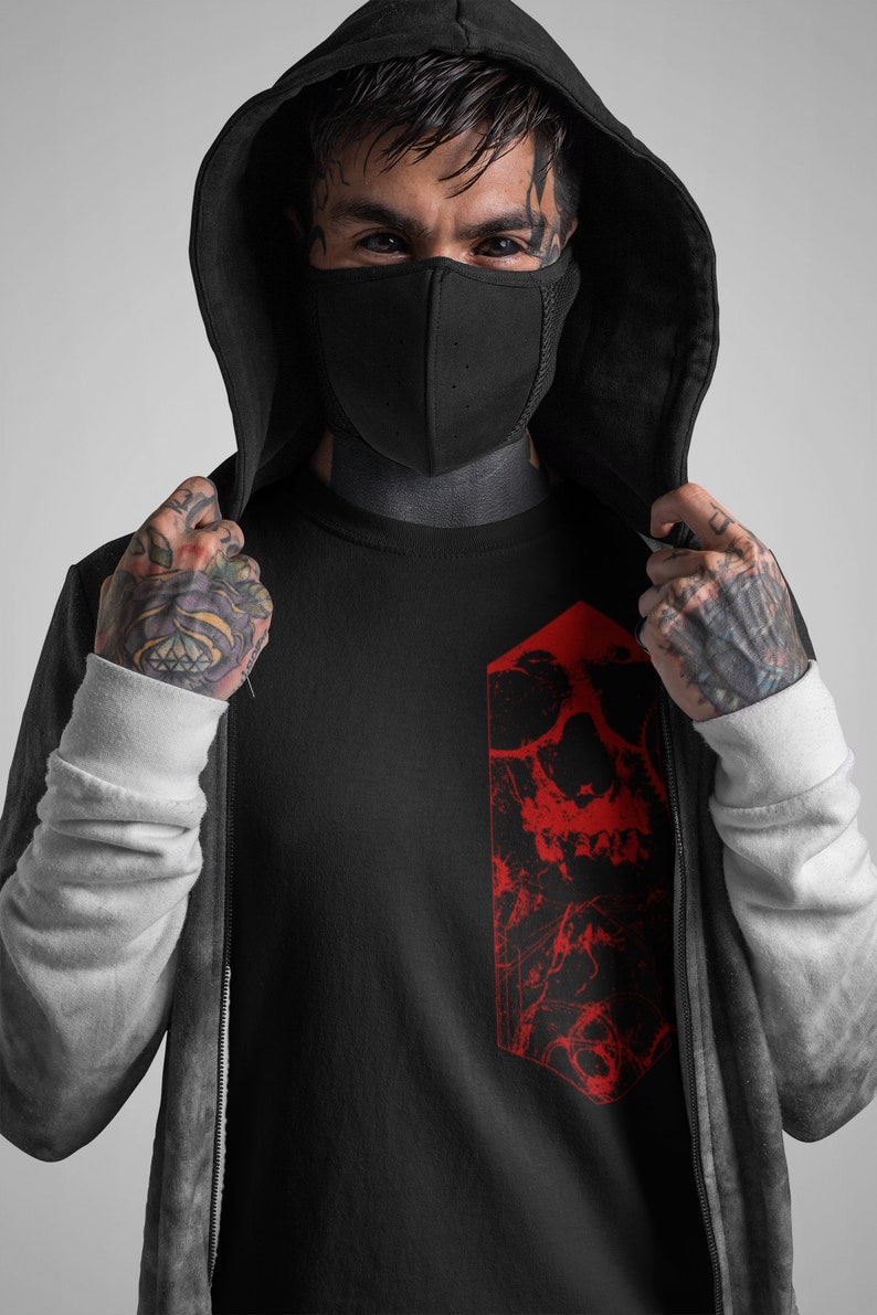 K&ouml;nnte beinhalten: Schwarzes T-Shirt mit einem roten Totenkopf-Motiv. Der Totenkopf ist stilisiert und hat ein gezacktes, geometrisches Design.