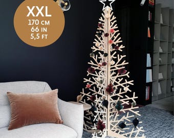 May include: A large wooden Christmas tree with a star on top and colorful paper ornaments. The tree is 5.5 feet tall and is decorated with red, pink, and green ornaments. The tree is standing in a room with a couch and a bookshelf in the background. XXL 170 CM 66 IN 5,5 FT