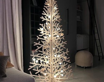 May include: A wooden Christmas tree with a star on top and white lights. The tree is standing in a room with a white floor and a couch in the background.