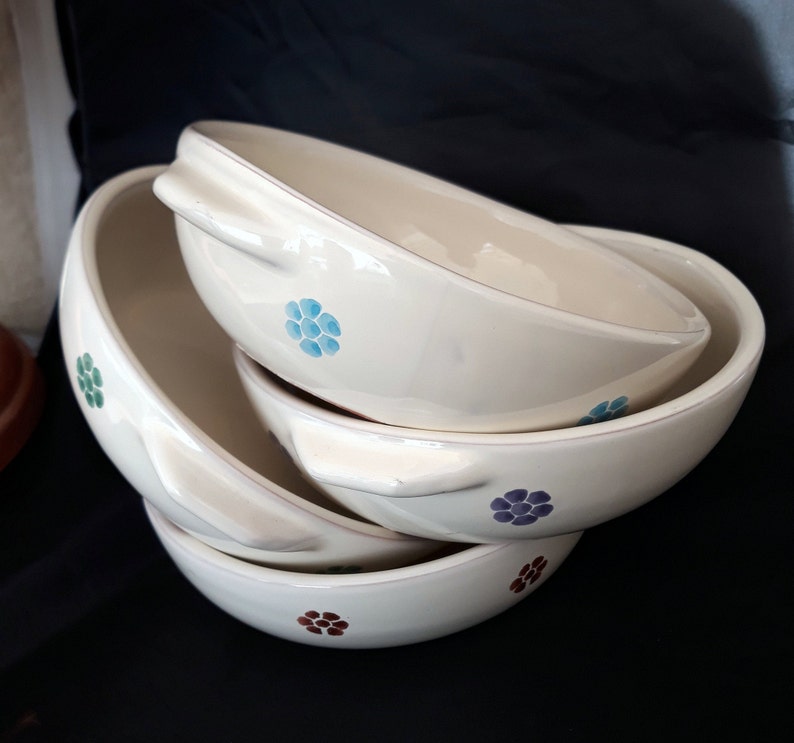 May include: Three white ceramic bowls with floral designs in blue, green, purple, and brown. The bowls are stacked on top of each other.