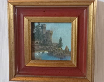 May include: Small framed painting depicting a castle on a rocky shore with a blue sky and water. The frame is a combination of gold and red, adding a classic touch to the artwork. The painting is a landscape scene.