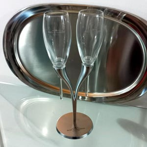 May include: Two silver champagne flutes with a silver base, the base is engraved with the words "Moët & Chandon".