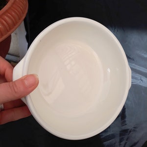 May include: White ceramic bowl with a smooth, glossy finish. The bowl has a rounded shape and a slightly flared rim.