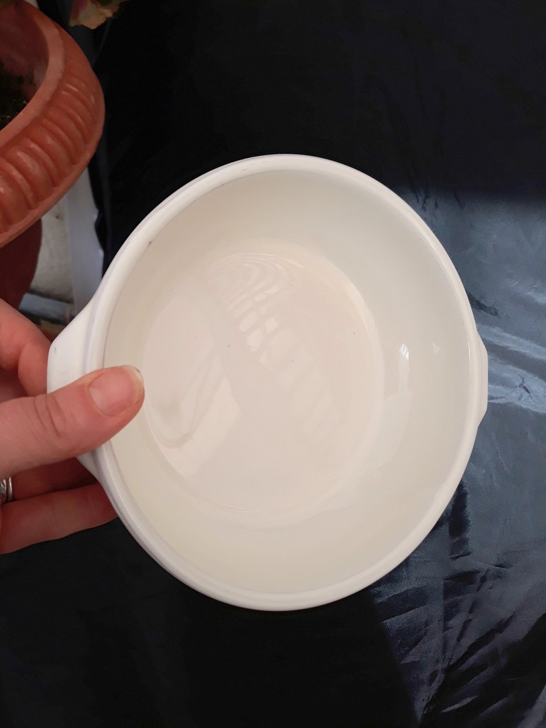 May include: White ceramic bowl with a smooth, glossy finish. The bowl has a rounded shape and a slightly flared rim.