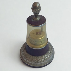 May include: An antique barometer with a clear glass dome, a brass dial, and a decorative metal base. The barometer has a dark wooden section and a metal top. The dial shows numbers from 30 to 40.