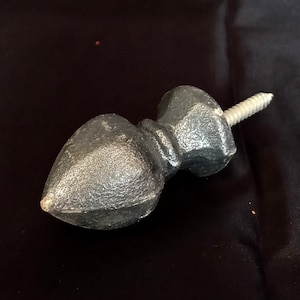 Puede incluir: Un pomo decorativo de color plateado para muebles con una superficie texturizada y un extremo puntiagudo. El pomo está unido a un tornillo plateado. El pomo es probablemente de metal y está diseñado para su uso en cajones o armarios.