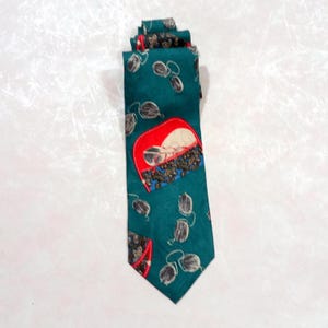 May include: Teal necktie with a repeating pattern of gray and white shapes. The tie features a red, white, and blue patch with a design of sunglasses. The tie is made of a smooth fabric.