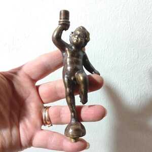 Könnte beinhalten: Eine weiße Keramik-Tasse mit schwarzem Henkel und dem Text "But First, Coffee" in fetter, schwarzer Schrift. Die Tasse steht vor einem verschwommenen Hintergrund, der eine gemütliche Umgebung suggeriert. Die Tasse ist etwa 10 cm hoch.