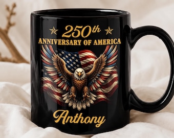 Op de afbeelding: Een zwarte keramische mok met een afbeelding van een Amerikaanse zeearend met gespreide vleugels voor een Amerikaanse vlag. Bovenaan staat 250th ANNIVERSARY OF AMERICA en onderaan de naam Anthony in gouden letters, geflankeerd door twee sterren.