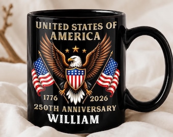 Op de afbeelding: Een zwarte keramische mok met een afbeelding van een Amerikaanse zeearend met een schild, geflankeerd door twee Amerikaanse vlaggen. De tekst luidt UNITED STATES OF AMERICA, 1776 2026 250TH ANNIVERSARY en de naam WILLIAM in witte hoofdletters.