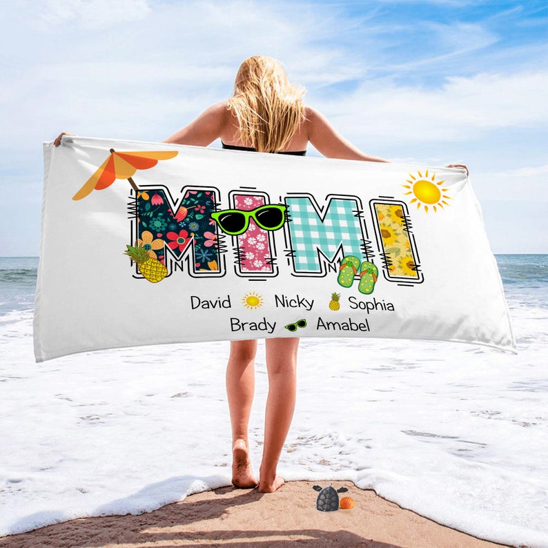 May include: White beach towel with the word "MIMI" in colourful patchwork letters. The letters are decorated with flowers, pineapples, sunglasses, and flip-flops. Below the word "MIMI" are the names David, Nicky, Brady, Sophia, and Amabel.