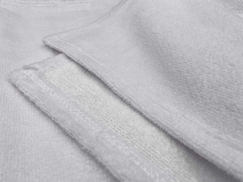 May include: Two white microfiber cloths with a stitched edge. The cloths are folded and layered on top of each other.