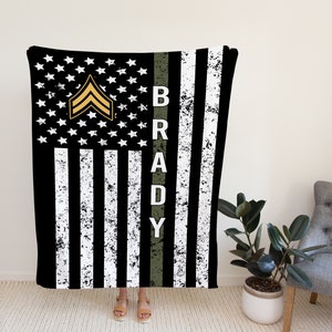 May include: Black and white American flag with a green stripe down the side. The stripe has the name "BRADY" in white letters. A gold military rank insignia is on the flag.