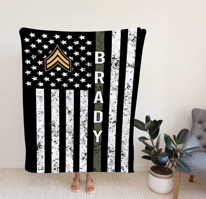 May include: Black and white American flag with a green stripe down the side. The stripe has the name "BRADY" in white letters. A gold military rank insignia is on the flag.