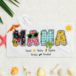 May include: White beach towel with the word "MAMA" spelled out in colourful letters. Each letter is decorated with a different summer-themed pattern. The letters are outlined in black and have stitching details. Below the word "MAMA" are the names "David, Nicky, Sophia, Brady, Amabel" written in black text.