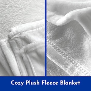May include: Close-up of a white plush fleece blanket. The blanket is folded and shows the soft texture and stitching.