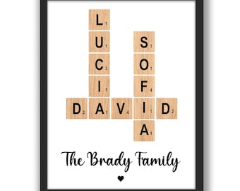 May include: A framed print with a white background featuring a scrabble tile crossword puzzle spelling out the names "LUCI" and "DAVID" with the words "The Brady Family" below.