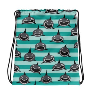 May include: A turquoise and white striped drawstring bag with a repeating pattern of black cartoon sharks with white teeth.