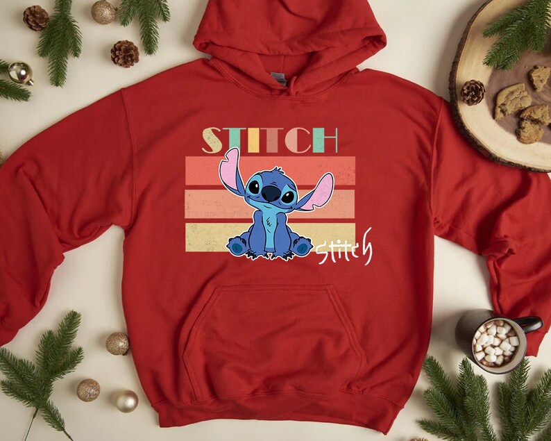 May include: Red hooded sweatshirt with a retro-style graphic of Stitch from Lilo & Stitch. The graphic features Stitch with a blue and light blue color scheme and the text "Stitch" and "Stitchy" in a rainbow color scheme.