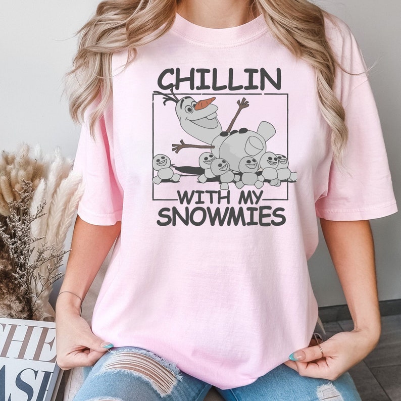 May include: Pink t-shirt with a graphic of Olaf from Frozen surrounded by snowmen. The text on the shirt reads "Chillin' with my snowmies".