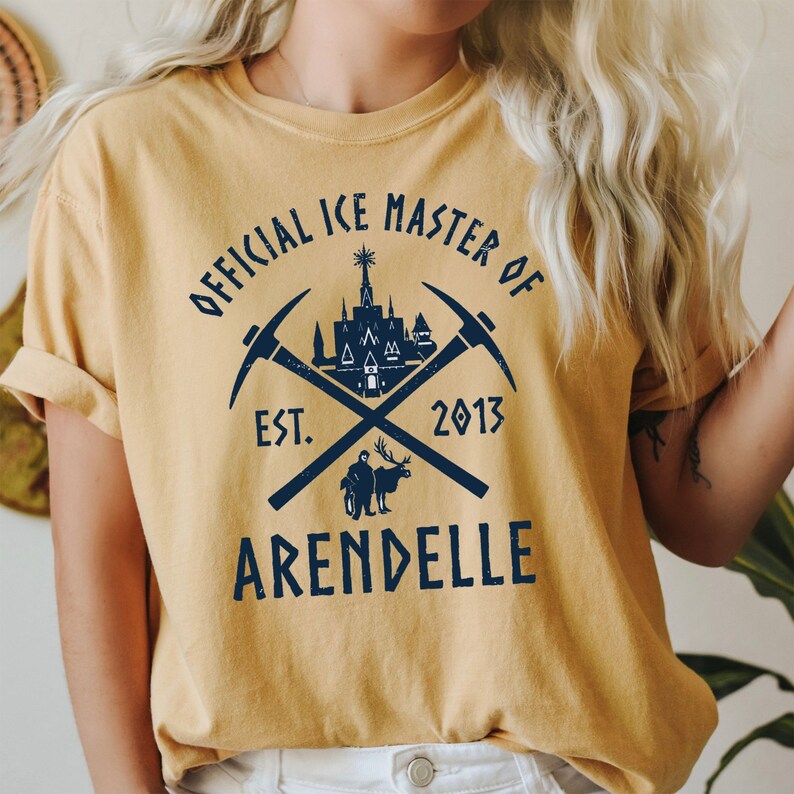 May include: A yellow t-shirt with a blue graphic design that says "Official Ice Master of Arendelle" with a castle, crossed pickaxes, and the text "Est. 2013".