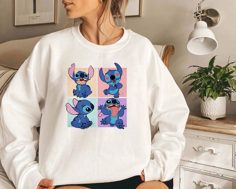 May include: White sweatshirt featuring a colorful graphic of the character Stitch from the animated film Lilo & Stitch. The design showcases Stitch in four different poses, each set against a pastel background. A comfortable, casual top.
