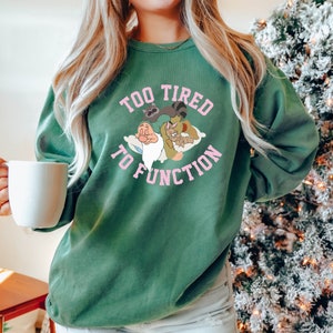 May include: Green sweatshirt with a pink graphic of cartoon characters sleeping on a cloud with the text "Too Tired To Function".
