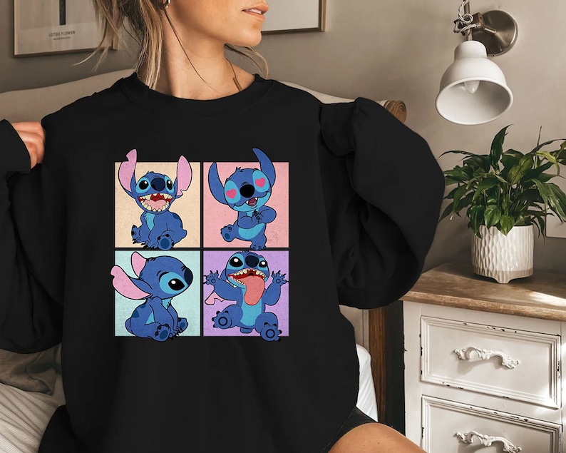 May include: Black sweatshirt featuring a colorful graphic of the character Stitch from the animated film Lilo & Stitch. The graphic shows Stitch in four different poses, each in a separate square with a different pastel background.