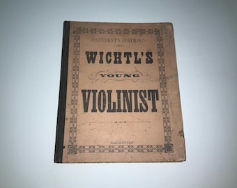 May include: Vintage "Wichtl's Young Violinist" student's edition music book. The cover is tan with black text and decorative borders. The book's spine is black. The title is prominently displayed, with the word "Young" in a decorative script font.