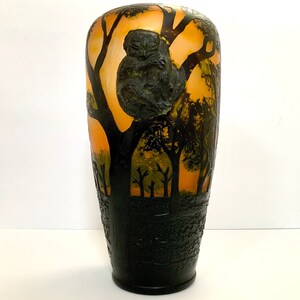 May include: A vintage glass vase with an amber and black colour scheme. The vase features a silhouette of a sleeping animal in a tree, with a forest scene in the background.