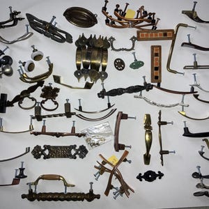 Grande lote de ferragens diversas, incluindo puxadores, maçanetas e espelhos em latão e cobre.