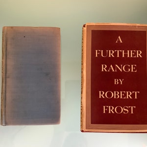 May include: Two books, one with a blue cover and the other with a red cover. The red book has the title "A FURTHER RANGE BY ROBERT FROST" printed in gold lettering.