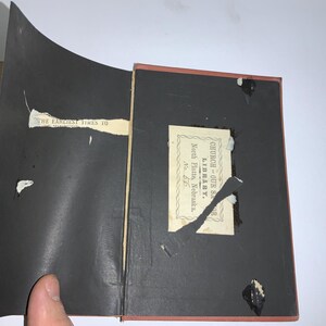 以下が含まれることがあります： 黒い表紙の本のクローズアップ。ラベルには「Church Our Savior Library, North Platte, Nebraska, No. 66」と書いてあります。