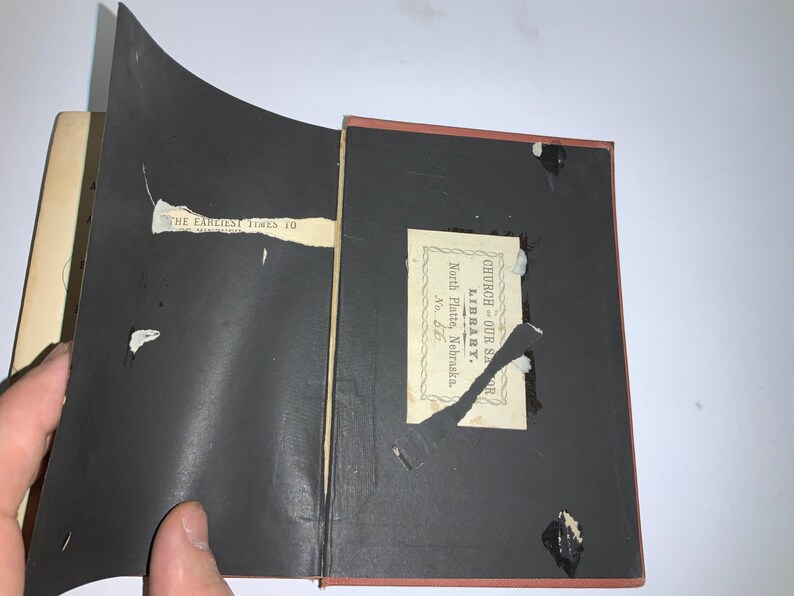 以下が含まれることがあります： 黒い表紙の本のクローズアップ。ラベルには「Church Our Savior Library, North Platte, Nebraska, No. 66」と書いてあります。