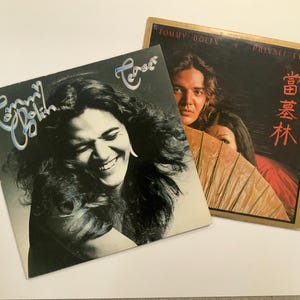 Könnte beinhalten: Zwei Vintage-Vinyl-Schallplattenalben. Ein Albumcover zeigt eine lächelnde Frau mit langen Haaren, den Text "Tommy Bolin" und "Teaser". Das andere Albumcover zeigt einen Mann und eine Frau mit dem Text "Tommy Bolin Private Eyes" und japanischen Schriftzeichen.