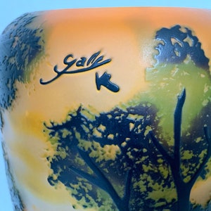May include: A yellow and green glass vase with a black tree design and the signature "Gall&eacute;" on the front.
