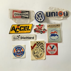 Pode incluir: Uma coleção de decalques e patches vintage de automóveis e corridas. Inclui Champion, Accel, Sears DieHard, Canadian Tire, American Freedom Train, Valvoline Racing Oil e outros.