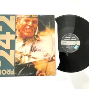 May include: A vinyl record and album cover for the band Front 242. The album cover is green with the band name and the number 242 in gold. The record is black with the album title "Politics of Pressure".