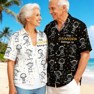 May include: Matching button-down shirts, one black and one white, with a whimsical cartoon design. The black shirt reads "This GRANDPA Belongs to" and the white shirt says "This GRANDMA Belongs to". Both shirts feature names and star accents.