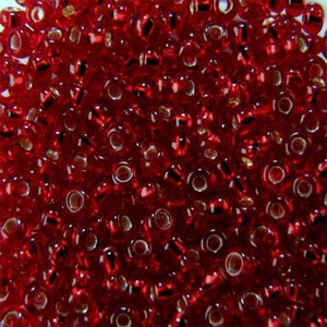 Puede incluir: Una gran cantidad de pequeñas cuentas de vidrio redondas de color rojo con un brillo metálico plateado.