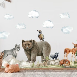 May include: A set of watercolor animal wall decals featuring a brown bear, a wolf, a deer, a fox, a rabbit, a quail, and a skunk. The decals are set against a backdrop of clouds and a pine tree.