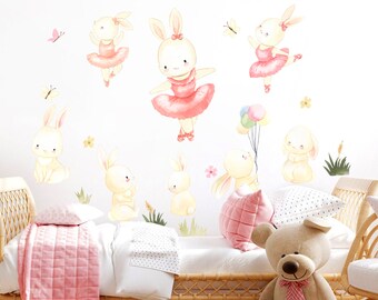 May include: A white wall with a set of watercolor bunny wall decals. The decals feature bunnies in pink tutus, holding balloons, and standing in grass. The decals are perfect for a child's bedroom.
