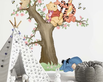 Puede incluir: Una calcomanía de pared con temática de Winnie the Pooh que presenta a Winnie the Pooh, Tigger, Piglet y un búho sentados en una rama de árbol con flores rosas. La calcomanía está en una pared blanca con un tipi y un conejito de peluche en primer plano.