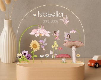May include: An arched clear acrylic plaque set in a light wood base, featuring printed illustrations of fairies, mushrooms, and various flowers. The text Isabella and 03.31.2025 are printed in white near the top of the transparent panel.