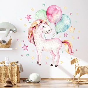 May include: A pink unicorn with a rainbow mane and tail holds three balloons, one pink, one green and one blue. The unicorn is surrounded by small stars and dots on a white background.