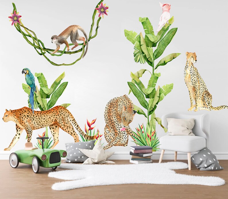 May include: A jungle-themed wall decal set featuring a monkey, a parrot, a pink flamingo, and two leopards. The decals are set against a white background with green banana leaves and pink flowers.