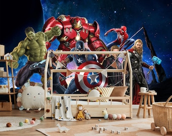 May include: A wooden house-shaped bed frame with a low platform, decorated with superhero characters including Hulk, Iron Man, Captain America, and Thor. The background features a cosmic scene. The bed is accessorized with pillows, a blanket, and toys.