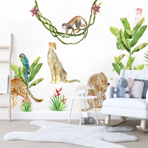 May include: A set of jungle animal wall decals featuring a monkey swinging from vines, a parrot, a pink bird, and four cheetahs. The decals are on a white wall with a white rocking chair, a wooden ladder, and a white rug.
