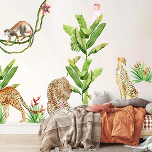 May include: A set of jungle animal wall decals featuring a cheetah, a monkey, a parrot, and a pink bird. The decals are on a white wall with a wooden bed and a brown blanket in the background.